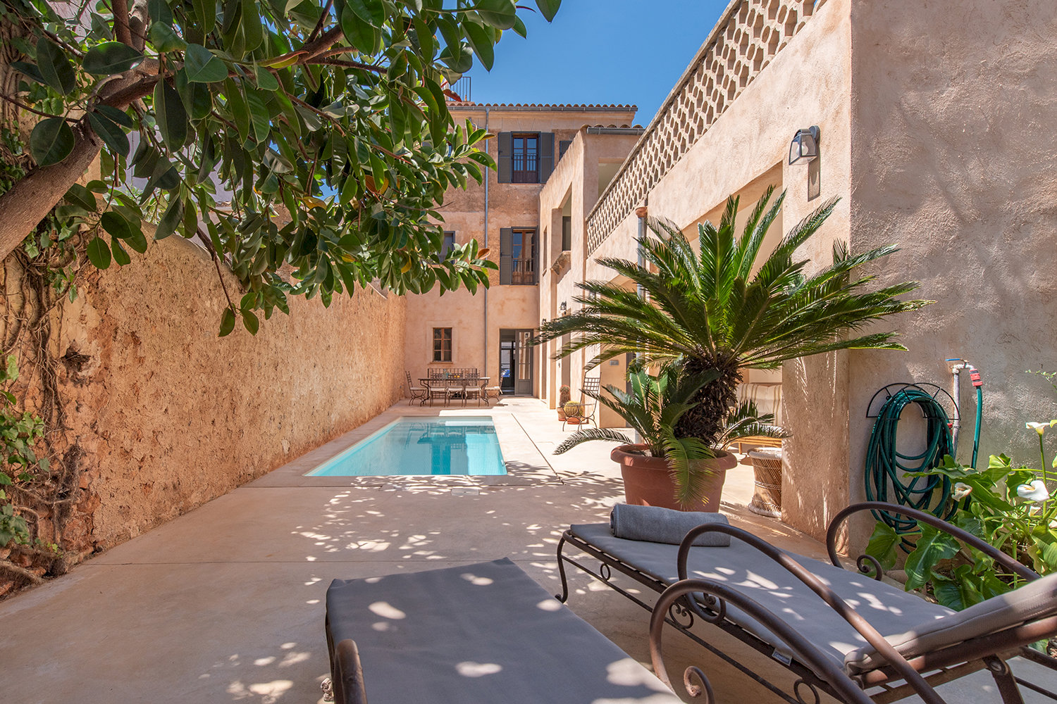 Spacious patio with sun deck, poolscape, and Mediterranean greenery
