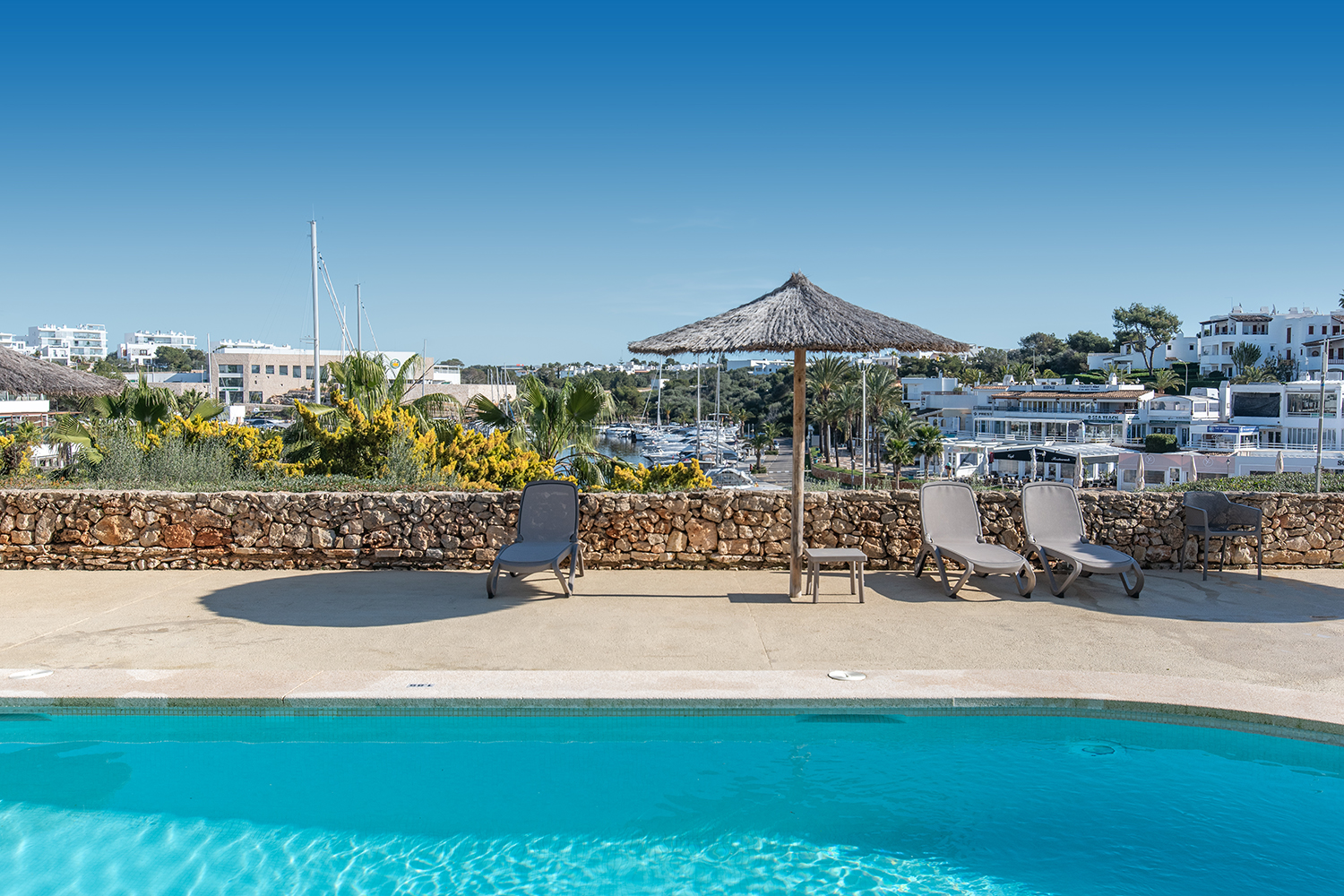 Pool terrace with sun loungers and marina view