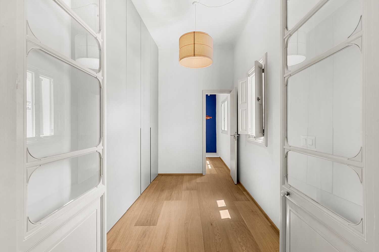 Generous dressing area with floor-to-ceiling fitted wardrobes and timber flooring